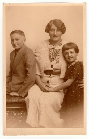 THE CZECHOSLOVAK REPUBLIC - CIRCA 1920s: Vintage photo shows family - mother, son and daughter. Retro black & white studio photography with sepia effect.のeditorial素材