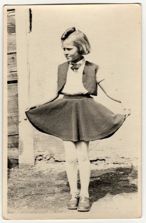 THE CZECHOSLOVAK REPUBLIC - CIRCA 1940s: Vintage photo shows a young girl outdoors. She shows her skirt proudly. Retro black & white photography.のeditorial素材