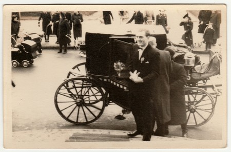 THE CZECHOSLOVAK REPUBLIC - CIRCA 1940s: Vintage photo shows a groom. A historical carriage (coach)  is on the background and historical prams too. Retro black & white photography.のeditorial素材