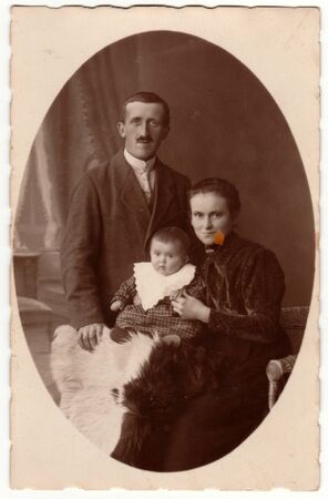 PRAHA (PRAGUE), THE CZECHOSLOVAK REPUBLIC - CIRCA 1923: Vintage photo shows family - father, mother and baby boy. Retro black & white studio photography of a bourgeois family.のeditorial素材
