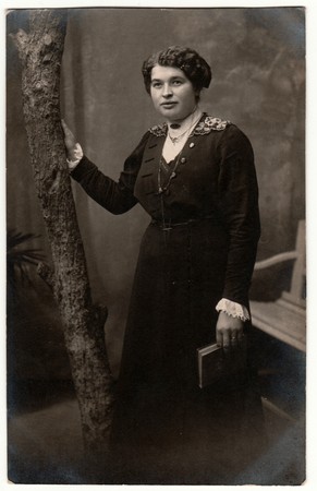 GERMANY - CIRCA 1920s: Vintage photo shows woman with short hair. Woman holds book. Retro black & white studio photography with sepia effect.のeditorial素材