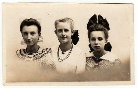 HAMBURG, GERMANY - CIRCA 1940s: Vintage photo shows a group of girls poses in the photography studio. Girls wears hair ribbon and some of them necklace ((string of) beads ). Retro black & white photography with sepia effect.のeditorial素材