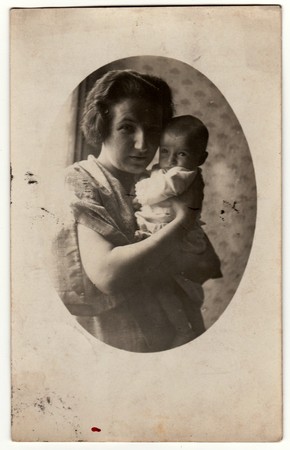 PRAHA (PRAGUE), THE CZECHOSLOVAK REPUBLIC - SEPTEMBER 15, 1927: Vintage photo shows mother cradles a small baby. Retro black & white photography.のeditorial素材