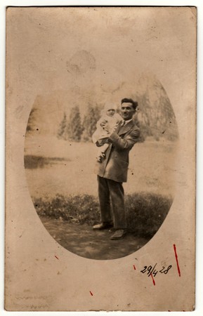 PRAHA (PRAGUE), THE CZECHOSLOVAK REPUBLIC - APRIL 29, 1928: Vintage photo shows man cradles a small baby. Retro black & white photography.のeditorial素材