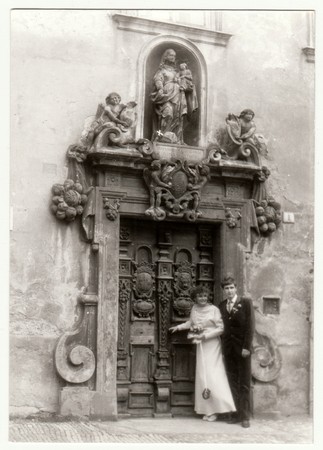 THE CZECHOSLOVAK SOCIALIST REPUBLIC - CIRCA 1980s: Vintage photo shows young newly-weds (bridal couple) in front of historical door. Retro black & white  photography.のeditorial素材