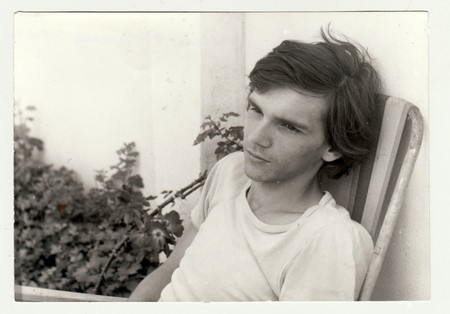THE CZECHOSLOVAK  SOCIALIST  REPUBLIC - JULY 1981: Vintage photo shows a teenager boy sits on camping chair outdoors.  Retro black & white  photography.のeditorial素材