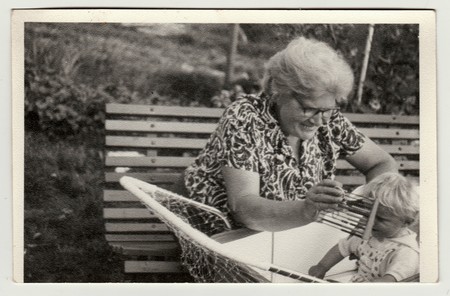 THE CZECHOSLOVAK SOCIALIST REPUBLIC - CIRCA 1950s: Vintage photo shows grandmother with a small baby in the pram (carriage). Grandmother holds abacus. Retro black & white  photographyのeditorial素材