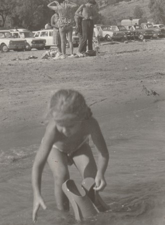 THE CZECHOSLOVAK  SOCIALIST  REPUBLIC - AUGUST 1977: Vintage photo shows  a small girl plays in the water with swimming fins. Holidays (vacation) theme. Retro black & white  photography.のeditorial素材