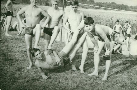THE CZECHOSLOVAK SOCIALIST REPUBLIC - CIRCA 1970s: Retro photo shows young men during summer time. Boys pose in front of volleyball net. Vintage photography.のeditorial素材
