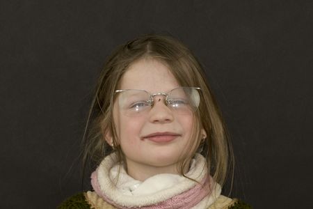 Portrait of a small girl on black background. Girl wears retro glasses. Authentic and real photo.