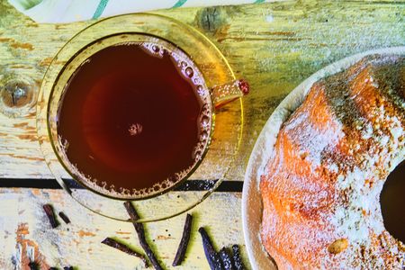 Old fashioned sand cake with cup of black tea and pieces of vanilla on wooden background. Egg-yolk sponge cake on rustic white background. Top view. Flat designの写真素材