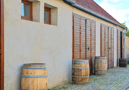 Old rustic wine barrels in front of modern wine cellar. Wine background in Europe. Czech Republic,...