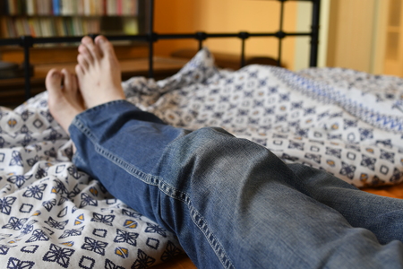 Men feet alone in a bed. Mens feet. Colored background. Close up