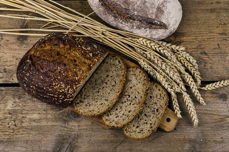 Loafs of bread, slices of bread and ears of grain on wood background. Rustic and rural concept. Close upの写真素材