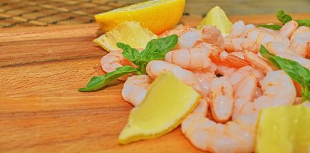 Cooked and peeled prawns with slices of lemon and leaves of basil on chopping board. Food photography. Healthy food. Bio recipe. Copy space.の写真素材