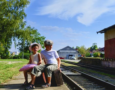 Adorable little girl and boy on a railway station, waiting for the train with vintage suitcases. Traveling, holiday and chilhood concept. Travel insurance concept. Vacation trip.の写真素材