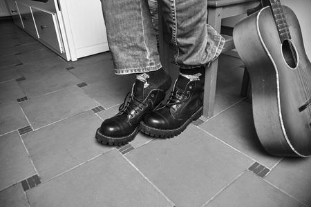 Rock and roll concept. Black boots and classic guitar. Black and white image
