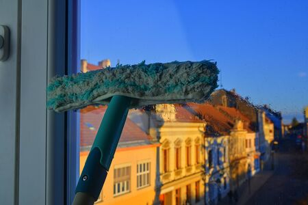 Cleaning windows with a squeegee. Cleaning concept. Washing window, close up.の写真素材