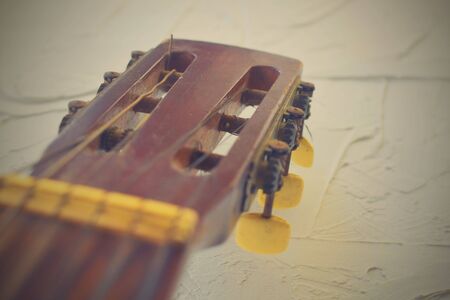 Old acoustic guitar head with tuning pegs. Retro haze