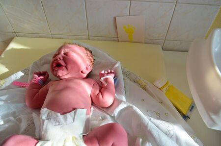 New born baby - girl with remainder of umbilical cord after successful childbirth. Real birthing and...