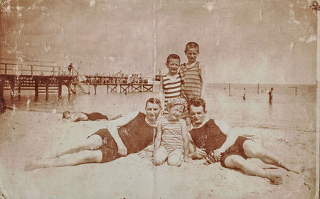 Vintage photo shows young boy with children at the seaside, the Baltic sea. Summer time. Vintage swimsuit and vintage swimming costume for children.のeditorial素材