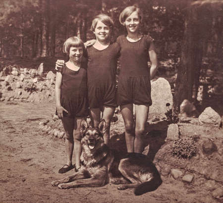 GERMANY - 1928: Vintage photo shows 3 young girls in the summer time. Girls wear swimmsuit and pose with German Shepherd Dog. Photo with sepia effect.のeditorial素材
