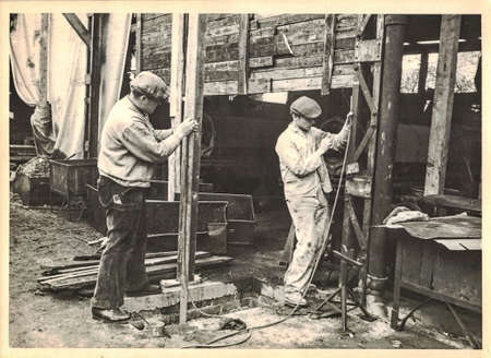 FRAUREUTH, EAST GERMANY - MAY 21, 1965: The retro photo shows building site in Communist bloc. Two bricklayers measures with water level. Former East Germany, 1960s.のeditorial素材