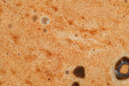 Hot chocolate foam close-up, macro. Abstract background. Black coffee with milk cream foam texture....