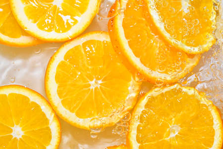 Oranges close-up in liquid with bubbles. Slices of juicy oranges in water. Close-up fresh slices of oranges on white backgroundの写真素材