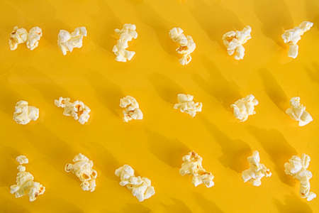 Close-up of popcorn on pastel yellow background. Cinema concept with many fluffy popcorn on yellow...
