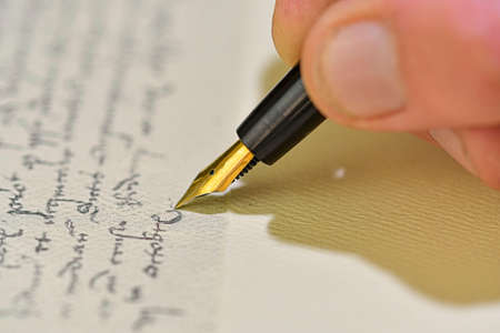 Antique style. Hand writing letter with fountain pen. Close-up of a male hand ready to write with an elegant fountain penの写真素材
