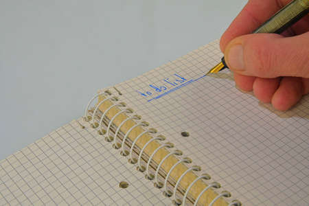 Man hand writing text - to do list - in notebook. Fountain pen, spiral notebook on table. Business,...