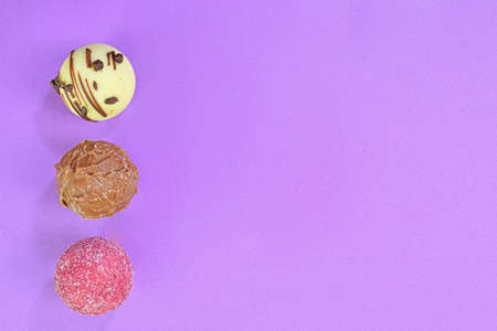 Chocolate bonbons or pralines on lilac background. Assortment of chocolate pralines on lilac background with copy space. Flat lay, top view.の写真素材