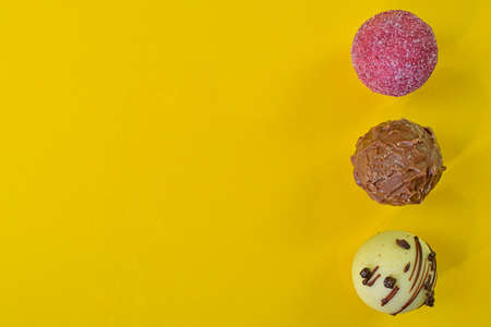 Collection of chocolate sweets on a colorful background. Chocolate pralines on a yellow background with copy space. Flat lay, top viewの写真素材