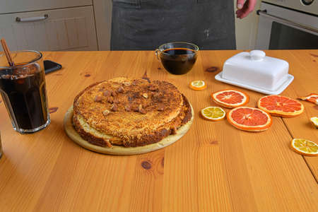 Close-up of a young caucasian man sprinkling powdered sugar on a cake. Placed on a rustic wooden tableの写真素材