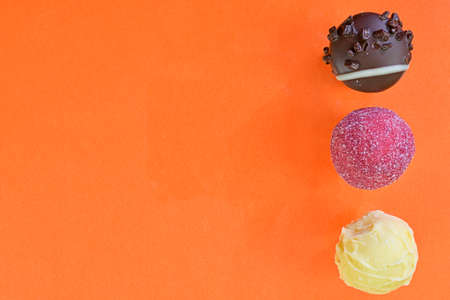 Collection of chocolate sweets on a colorful background. Chocolate pralines on an orange background with copy space. Flat lay, top viewの写真素材