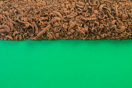 Scattered grated dark chocolate. Flat lay and large copy space. Chocolate shavings on a green...