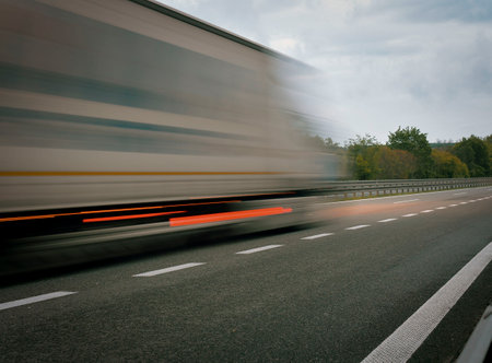 A truck driving on the highway at dusk. Motion blur on the highway. Evening shot of a truck. Concept of international transport and logisticsの写真素材