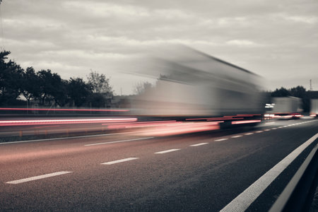 A truck driving on the highway at dusk. Motion blur on the highway. Evening shot of a truck. Concept of international transport and logistics. Almost monochrome imageの写真素材
