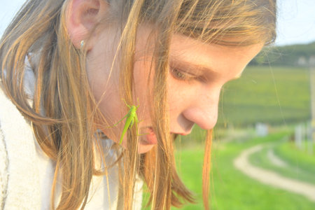 Romantic shot of a blonde girl with a grasshopper in her hairの写真素材