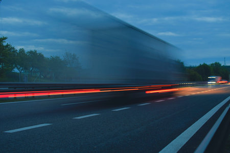 A truck driving on the highway at dawn. Blurred movement on the highway. Morning shot of a truck. Concept of international transport and logisticsの写真素材