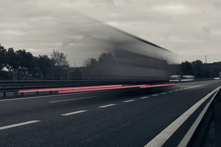 A truck driving on the highway at dusk. Motion blur on the highway. Evening shot of a truck. Concept of international transport and logistics. Almost monochrome imageの写真素材