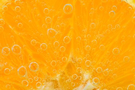 Slice of orange fruit in sparkling water. Orange fruit slice covered by bubbles in carbonated water. Orange fruit slice in water with bubbles. Close-up, macro horizontal imageの写真素材