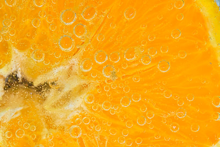 Close-up of an orange fruit slice in liquid with bubbles. Slice of ripe orange fruit in water. Close-up of fresh orange fruit slice covered by bubbles. Macro horizontal imageの写真素材