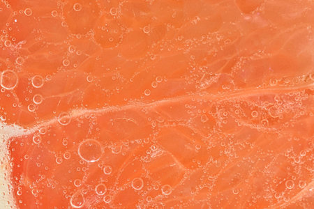Close-up of a grapefruit slice in liquid with bubbles. Slice of ripe grapefruit in water. Close-up...