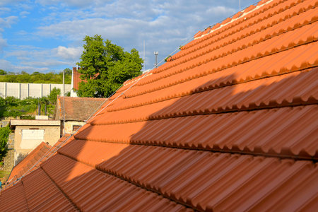 Newly covered roof. New roof covering with red clay tiles. Industrially manufactured tiles on the new roofing. Concept of construction, building work, and renovations on the houseの写真素材
