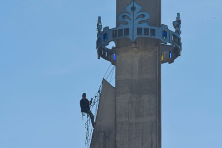 A skilled worker fixes the tower of a modern church. A roofer works on the tower of a modern building. The concept of working at height and safety at work.の写真素材