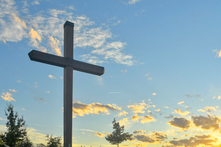 A large Christian cross in the landscape. A Christian cross illuminated by the sunset. The concept of Christianity, spirituality, and the concept of enlightenment.の写真素材