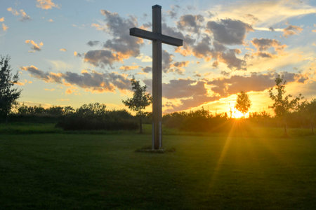 A large Christian cross in the scenery of a landscape. A Christian cross lighted by the setting sun. The concept of religion and Christianity.の写真素材