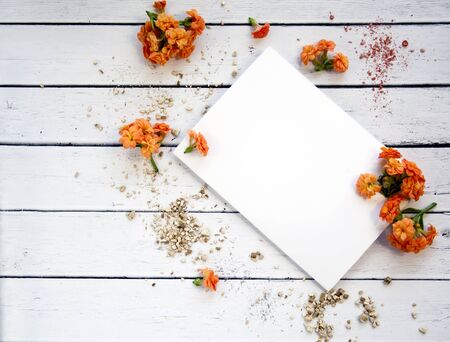 White sheet of paper with space for text with orange flowers and gold powder. Top view. Female desktop. A gentle romantic style.の写真素材